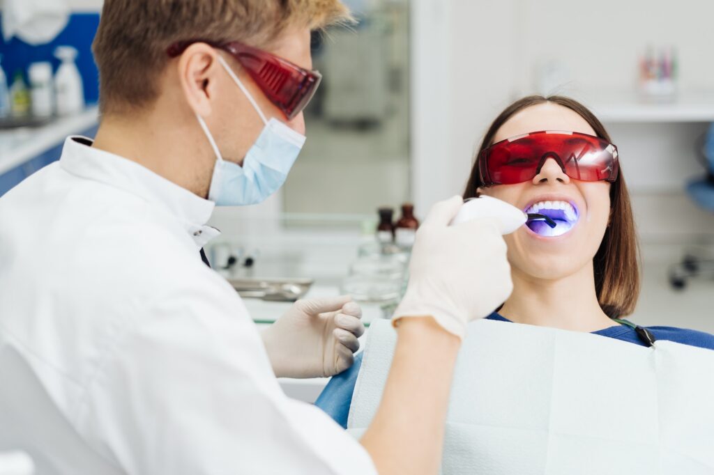 Whitening teeth procedure during visit at dentist.